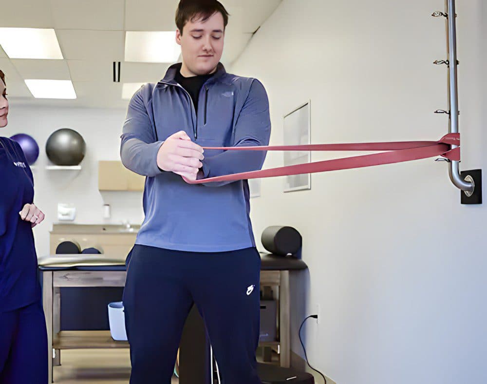 A physical therapist guiding a patient through a resistance-band exercise at Impact Health & Wellness